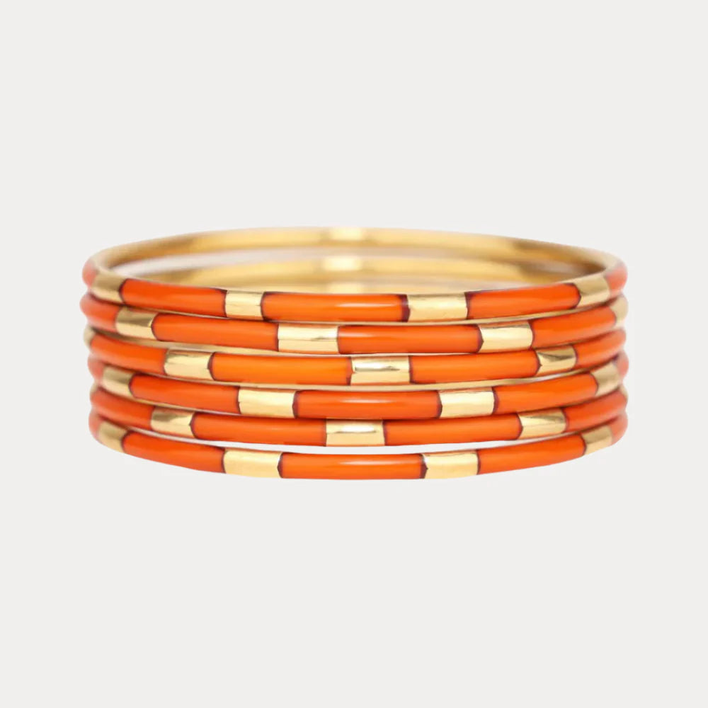 Six slim enamel bangles with alternating burnt orange and gold segments. Available in small, medium, and large sizes.