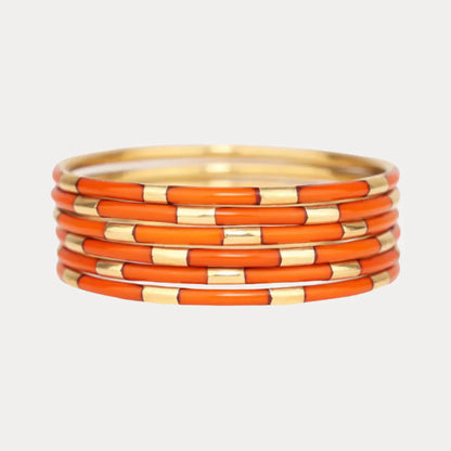 Six slim enamel bangles with alternating burnt orange and gold segments. Available in small, medium, and large sizes.