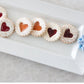 The Bread Tray Stripes: Rectangular white plate with a blue snowflake decoration, holding six cookies. Each cookie has a heart-shaped jam center (three red, three orange) and is dusted with powdered sugar. Available in sizes: Small, Medium, Large.