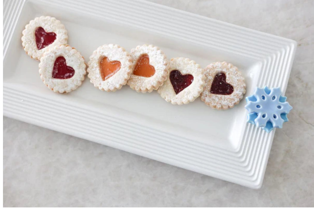 The Bread Tray Stripes: Rectangular white plate with a blue snowflake decoration, holding six cookies. Each cookie has a heart-shaped jam center (three red, three orange) and is dusted with powdered sugar. Available in sizes: Small, Medium, Large.