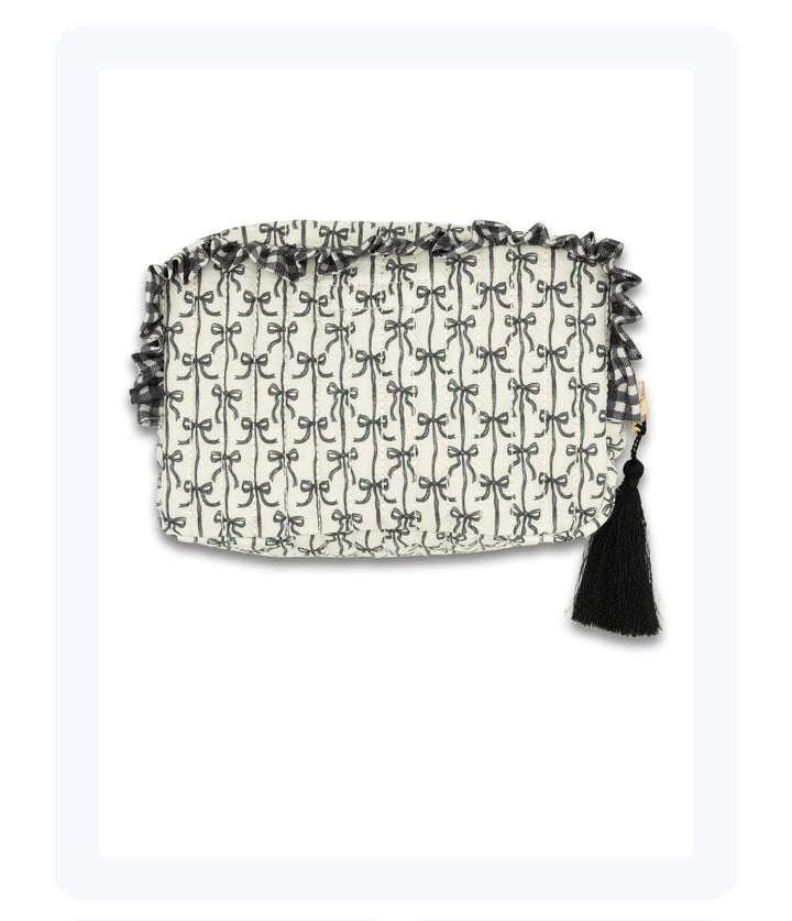 Rectangular white clutch with black bow pattern, ruffled top trim, black tassel accent. Sizes: Small, Medium, Large.