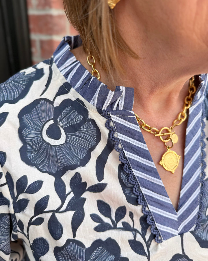 Bonnie Ruffle Floral Blouse in blue and white floral print with ruffled neckline and striped collar; available in sizes XS-XL.