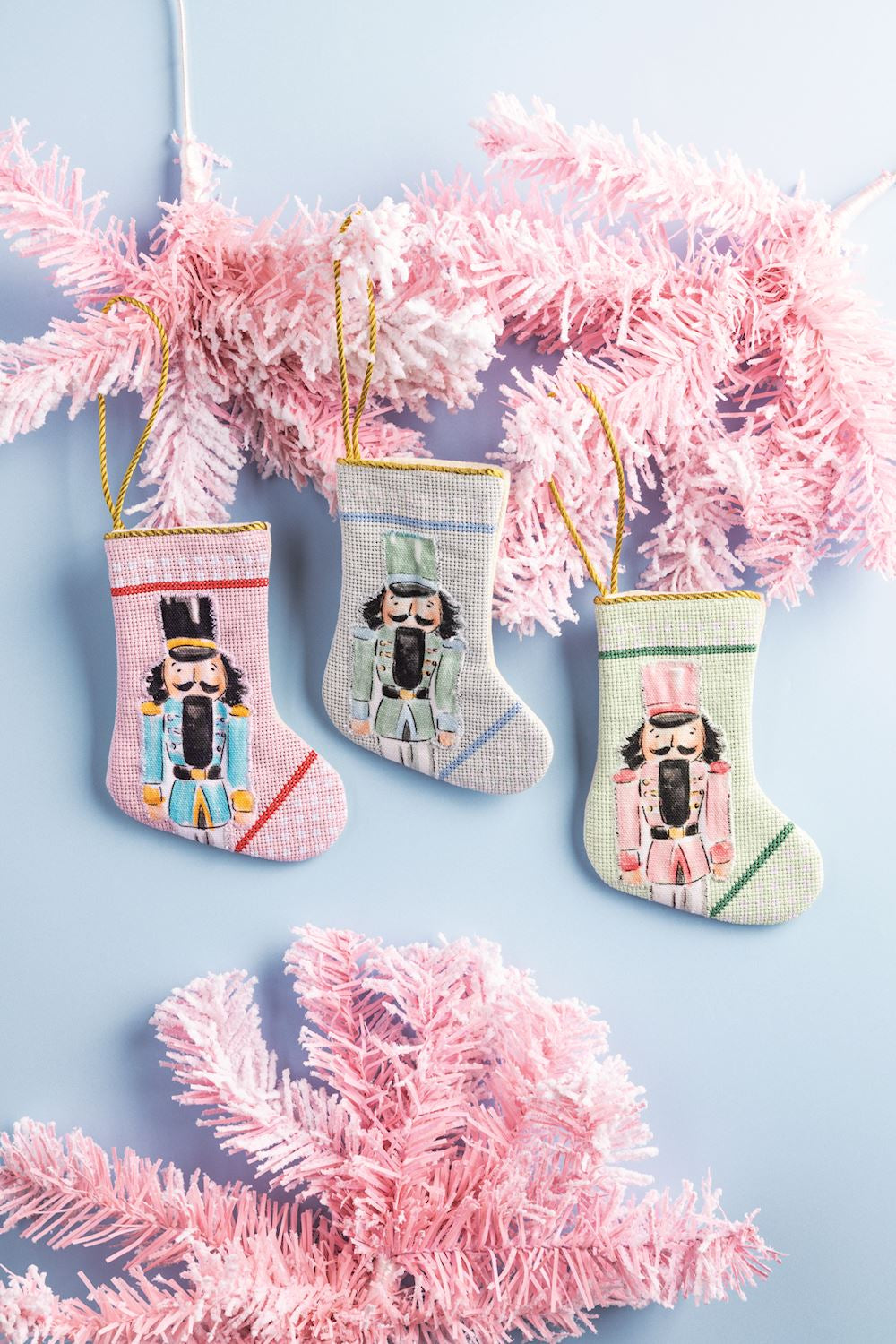 Three needlepoint nutcracker mini stockings with gold hanging loops.