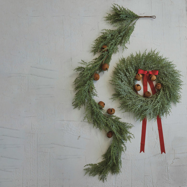 Faux cedar garland and matching wreath with rust-finished metal bells and red ribbon.