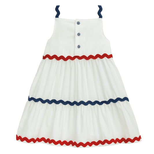 White sleeveless dress with blue straps, chest buttons, and red and blue zigzag trim. Available in sizes 2T-6.