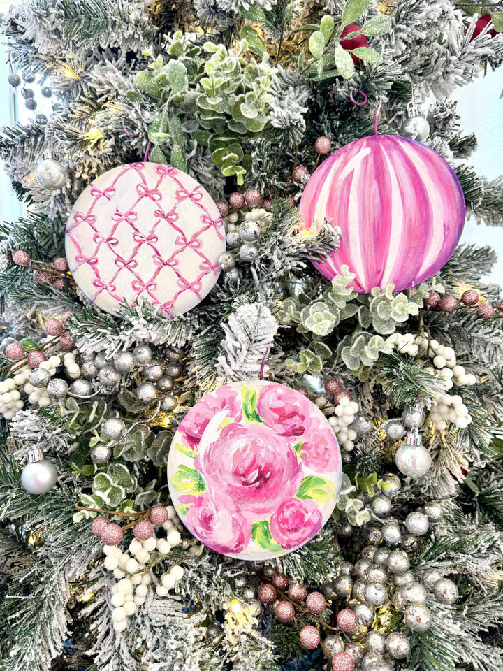 Three pink ball ornaments with bow grid, vertical stripe, and floral motif designs.