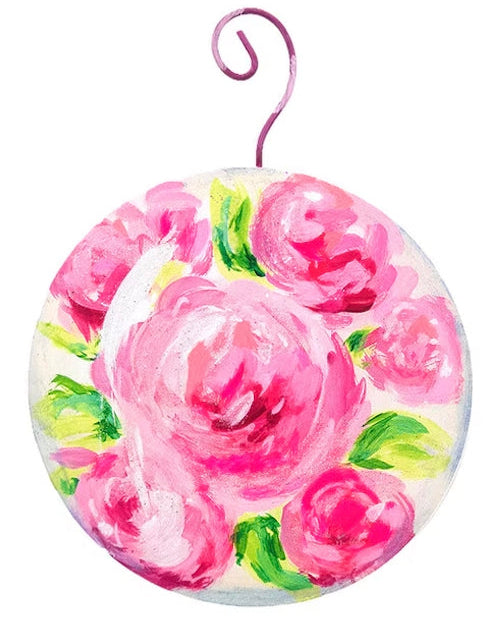 Round pink ball ornament with painted floral design and purple metal hook.