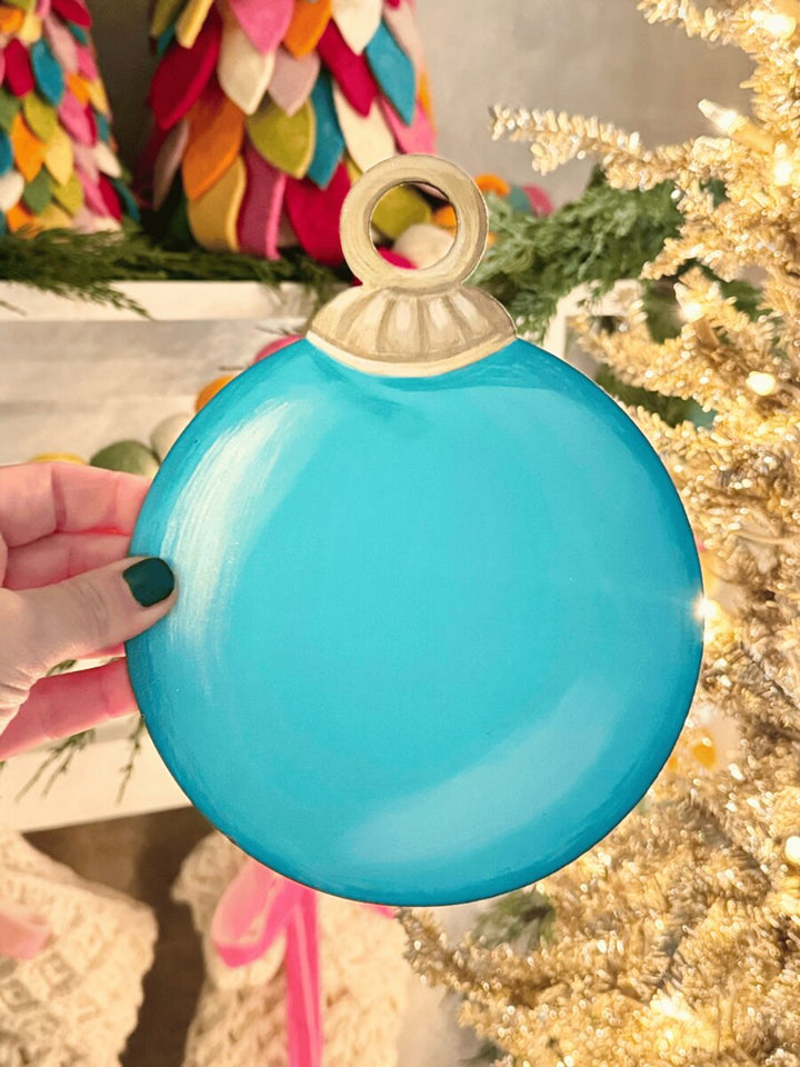 Circular turquoise round tree ornament magnet with a metallic topper.
