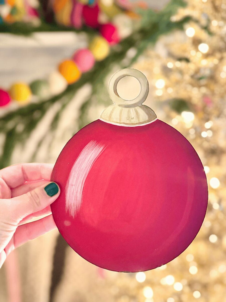 Round, red tree ornament magnet with a white cap.