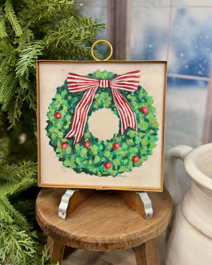 Mini Gallery Art Green Wreath with Red Ornaments: a square framed artwork of a green wreath with red ornaments and a red and white striped bow.