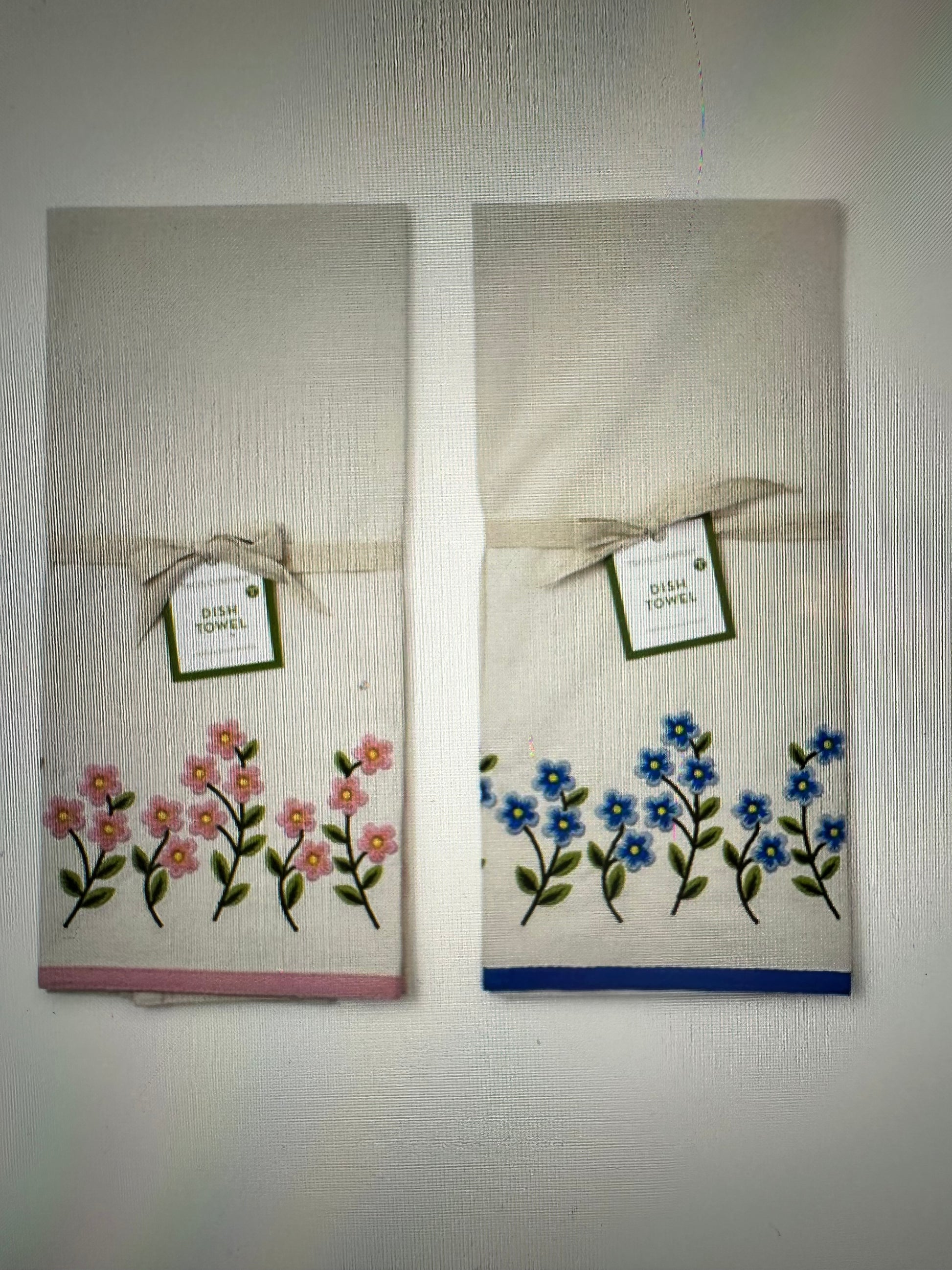 Two Forget-Me-Not dish towels with pink and blue flower embroidery, tag, and ribbon. Available in 16"x28".