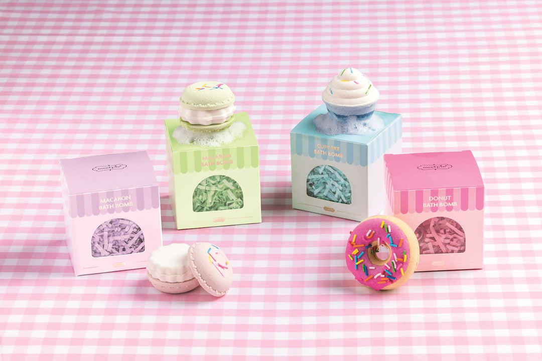 Café Bath Bomb set with four pastry-shaped bath bombs: a macaron, a cupcake, and a donut, packaged in individual square boxes.