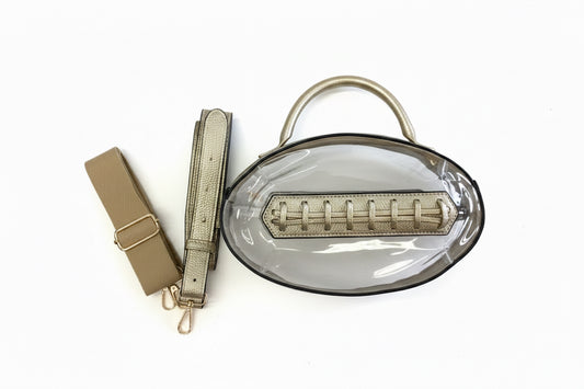 Clear oval football bag with metallic gold handles, trim, detachable strap, and interior zippered pouch. Available in one size.