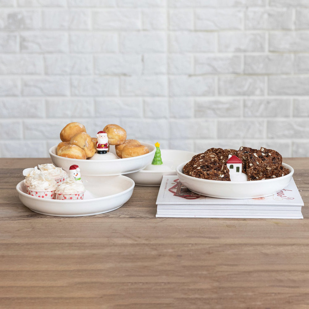 Three white round stoneware dishes with holiday figures in the center.
