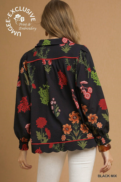 Black textured top with red, green, and orange floral embroidery, scalloped hem, puff sleeves. Sizes: XS-XXL.
