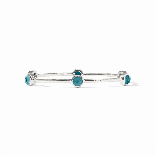 Silver bangle with five round blue bezel-set stones. Available in small, medium, and large sizes.
