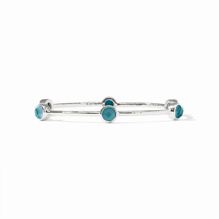 Silver bangle with five round blue bezel-set stones. Available in small, medium, and large sizes.