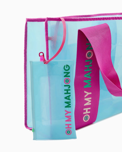 The Mahjong Beach Bag is a translucent blue tote with a bold pink strap and an attached matching zipper pouch, both featuring "OH MY MAHJONG" in colorful letters. Available sizes: Small, Medium, Large.