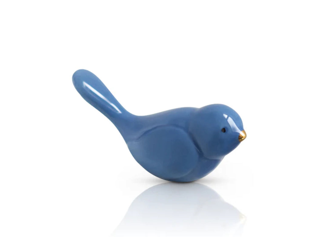Nora Fleming Minis figurine in glossy blue ceramic with shiny finish. Minimalist bird design, resting position, slightly raised tail, tiny golden beak. Sizes available: one-size.