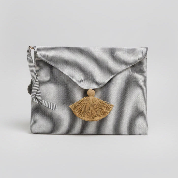 The Madison Wristlet Clutch is a compact striped fabric pouch with a fold-over flap, striped ribbon detail, and mustard-yellow tassel on the front. Available in small and medium sizes.