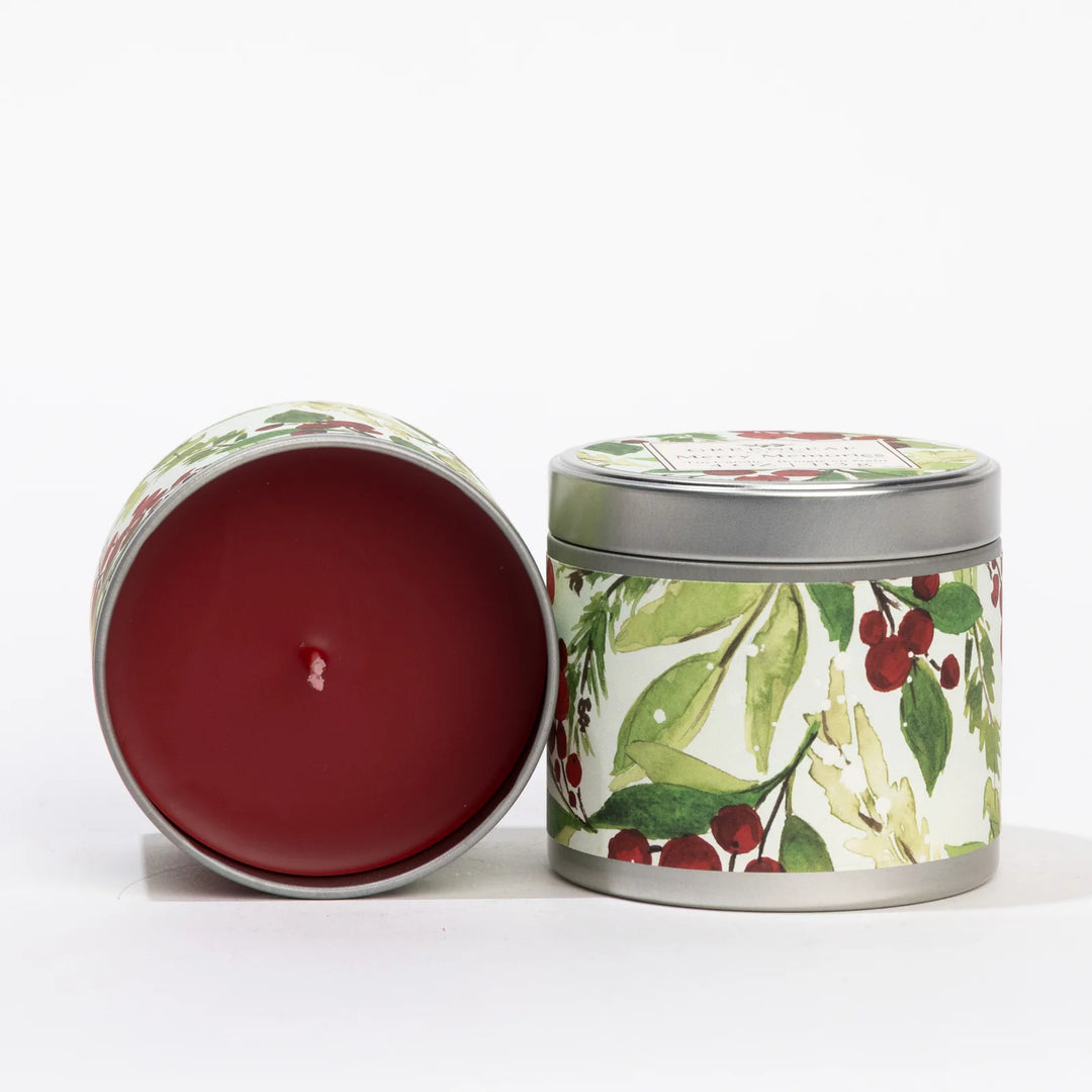 Two 4oz Merry Memories Tin Candles with holly and greenery watercolor patterns, one open with red wax and one closed.