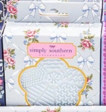 Floral-patterned Simply Southern box with clear window displays a textured, light blue Makeup Brush Cleanser inside with pink labels and white bows. Sizes available: standard.