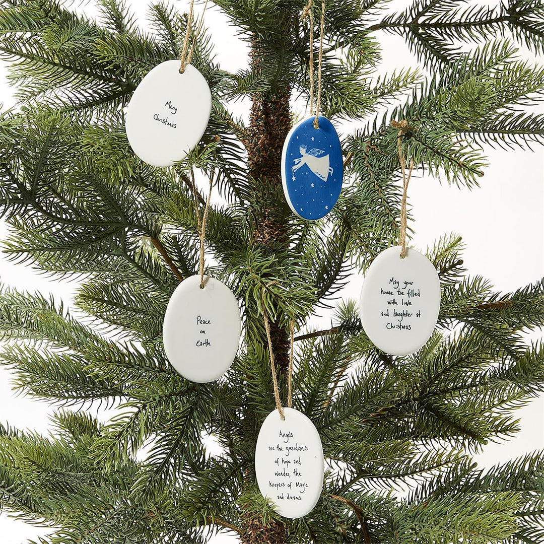 Five oval porcelain ornaments, including one blue ornament with a white angel and four white ornaments with holiday sentiments.