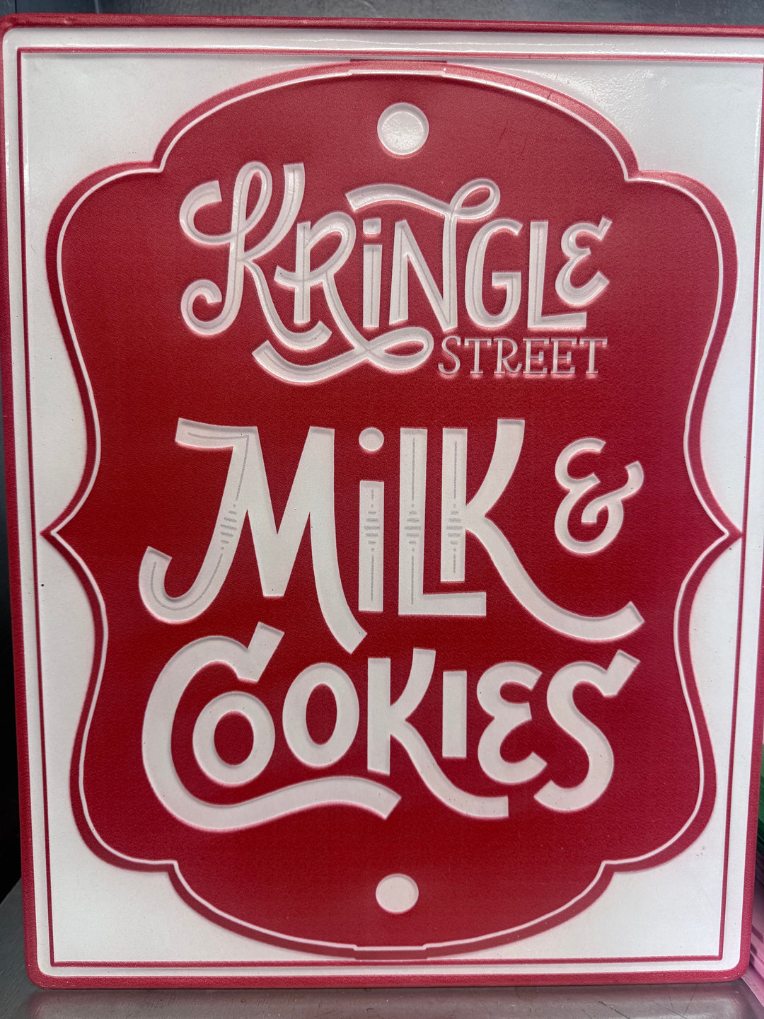 Red and white embossed “Kringle Street Milk &amp; Cookies” sign.