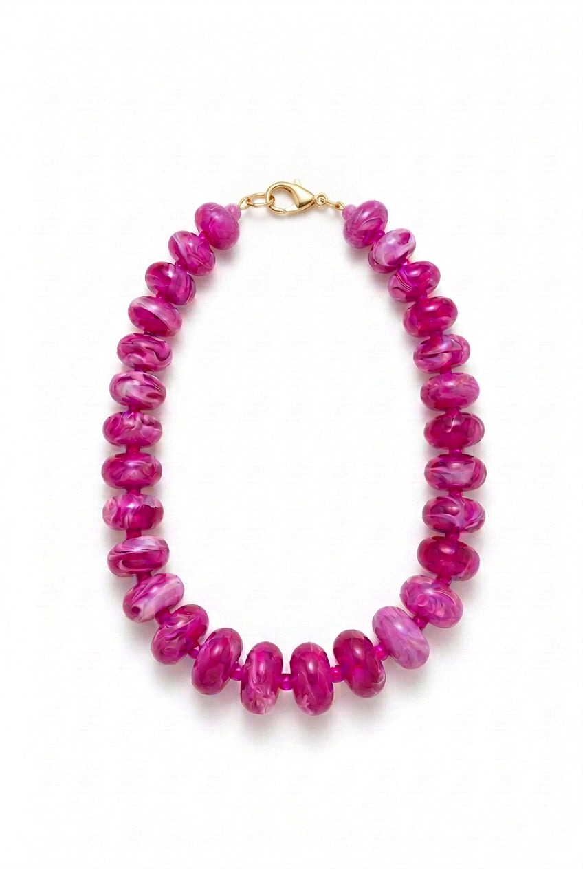 Oblong beaded necklace with translucent magenta marbled beads and a metal toggle clasp.