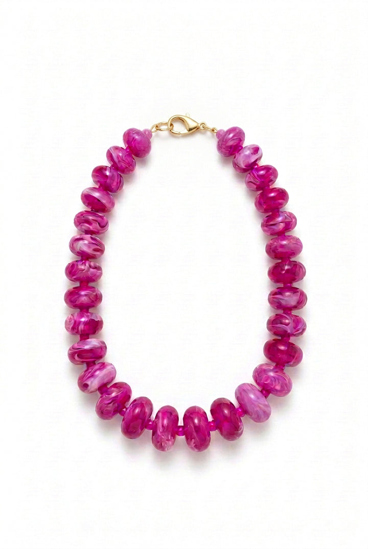 Oblong beaded necklace with translucent magenta marbled beads and a metal toggle clasp.