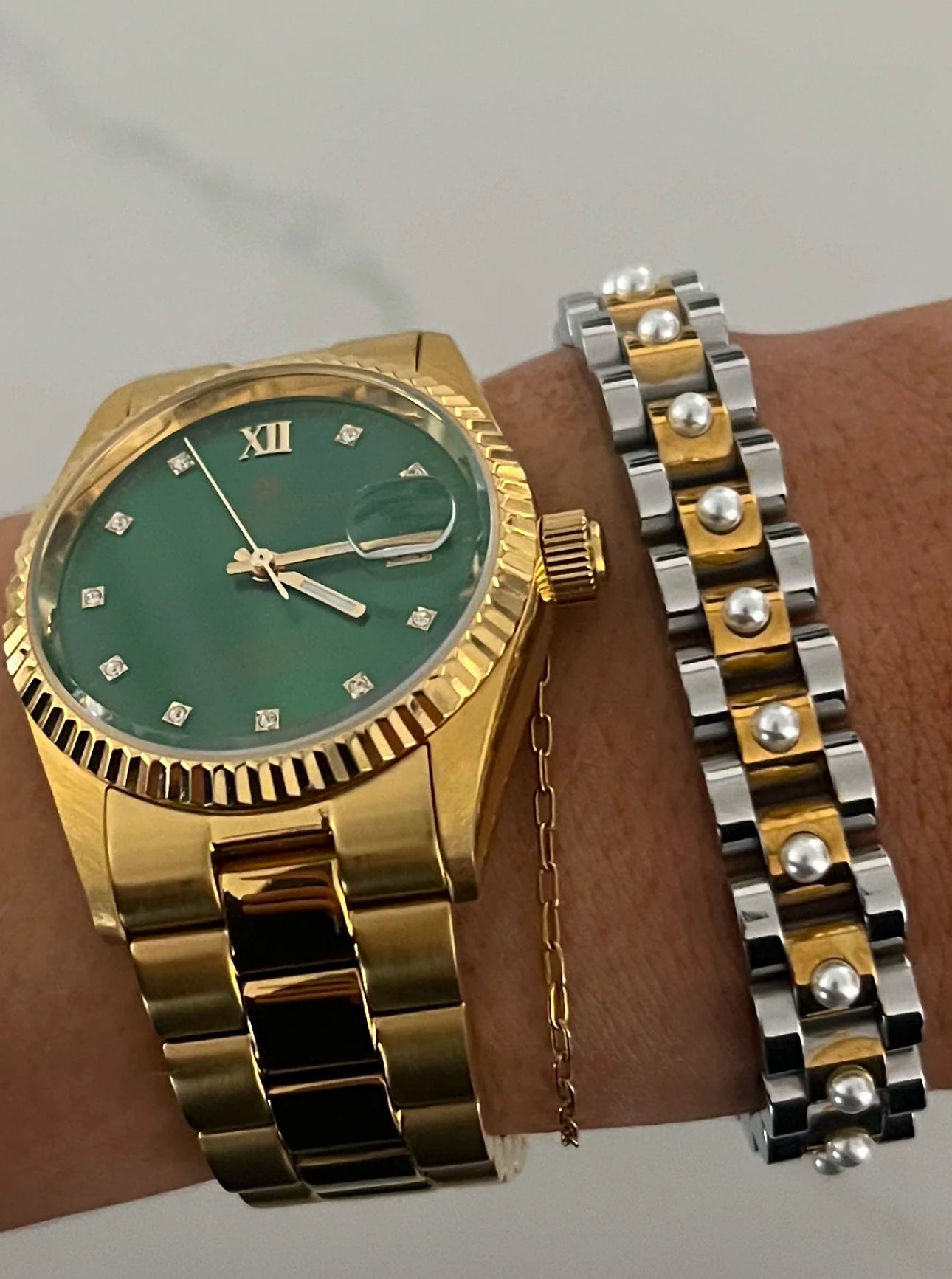 Gold wristwatch with thin gold watchband, green face, Roman numeral XII, and diamond hour markers. Sizes available: Small, Medium, Large.