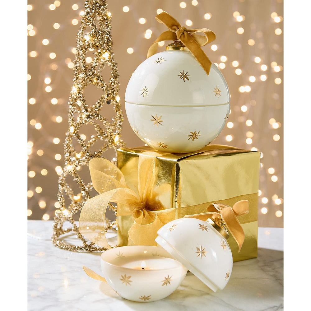 Two white ceramic Sparkling Rose Ornament Candles with gold stars, available in various sizes; one topped with a gold ribbon, the other open with a lit candle.