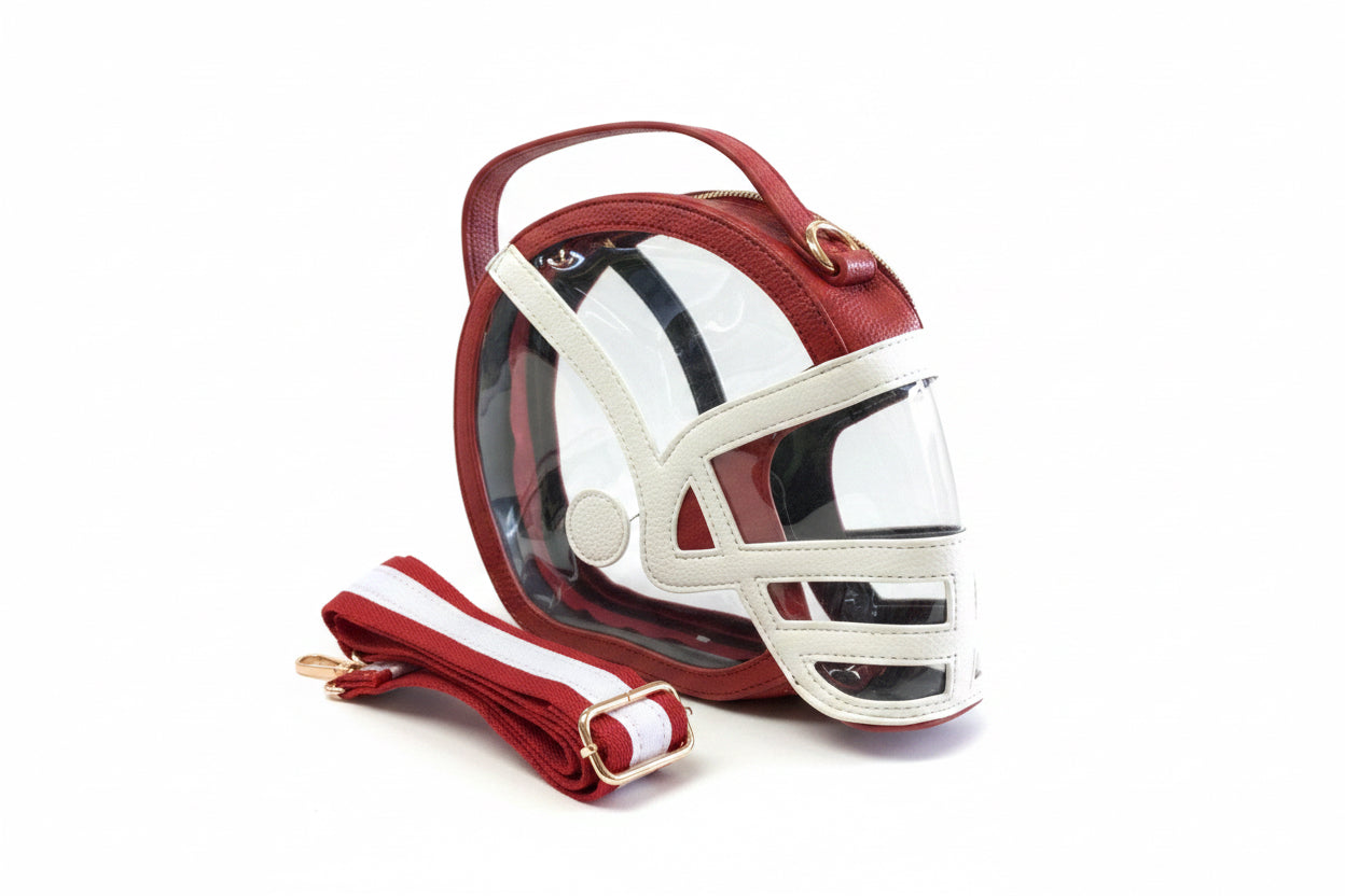 Helmet Game Day Bag shaped like a football helmet with red and white leather accents, transparent front panel, and removable red-and-white striped shoulder strap. Available in small, medium, and large sizes.