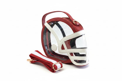Helmet Game Day Bag shaped like a football helmet with red and white leather accents, transparent front panel, and removable red-and-white striped shoulder strap. Available in small, medium, and large sizes.