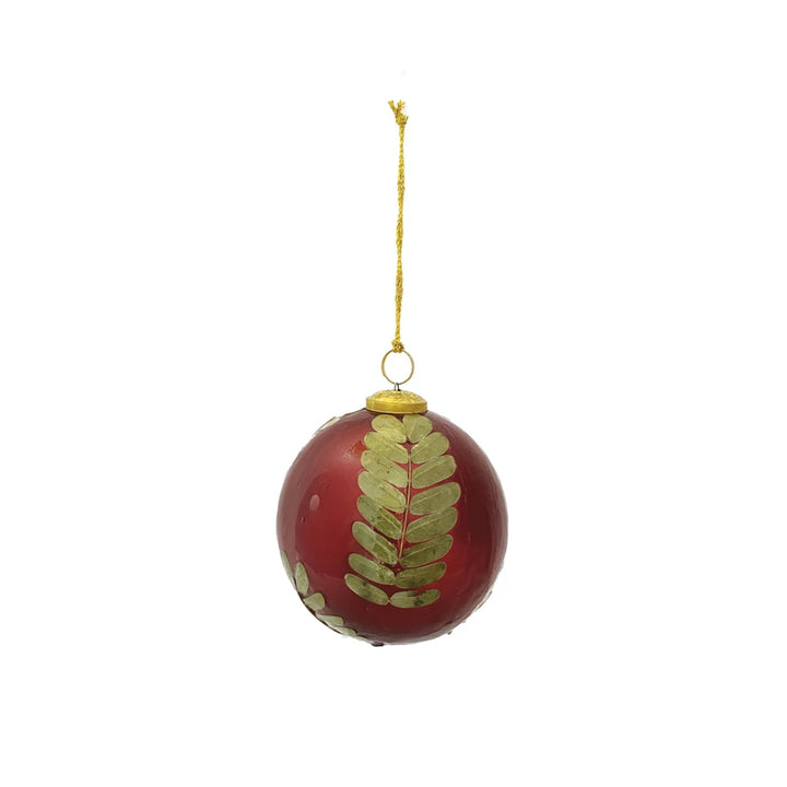 Red glass ball ornament with embedded gold-toned eucalyptus leaves and gold hanging string.