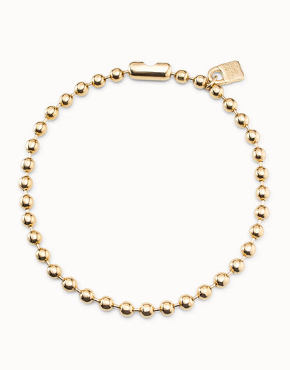 Short beaded necklace with evenly spaced round gold beads, rectangular padlock clasp, and small tag near clasp, handmade in Spain. Sizes available: short.