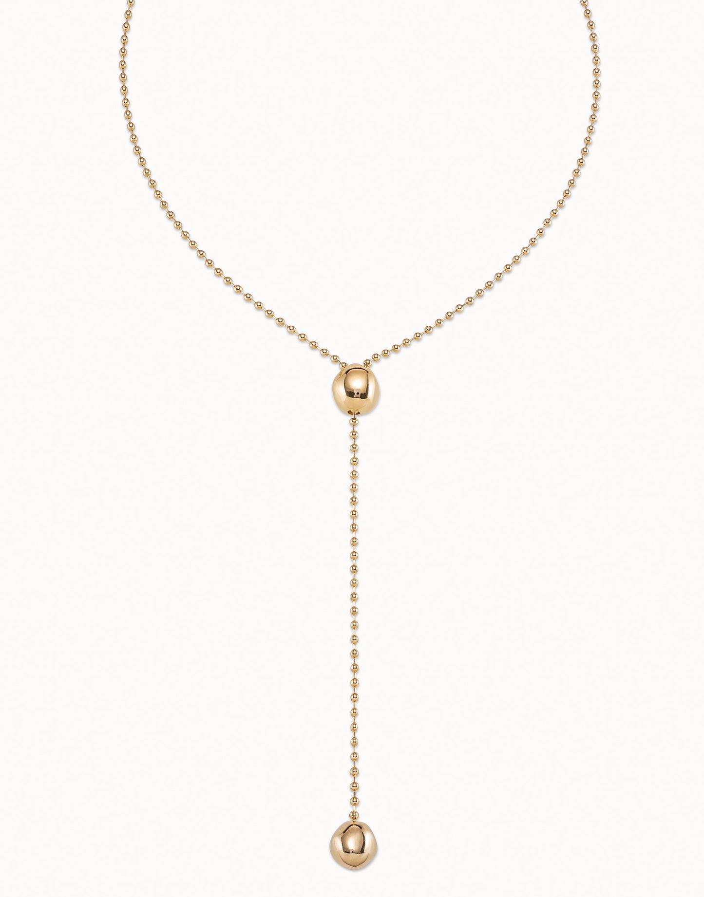 Long Adjustable Chain Necklace, handcrafted in Spain and plated in 18k gold. Features a beaded chain with a central bead, drop chain ending with a larger bead accent, and an adjustable clasp. Available in multiple sizes.