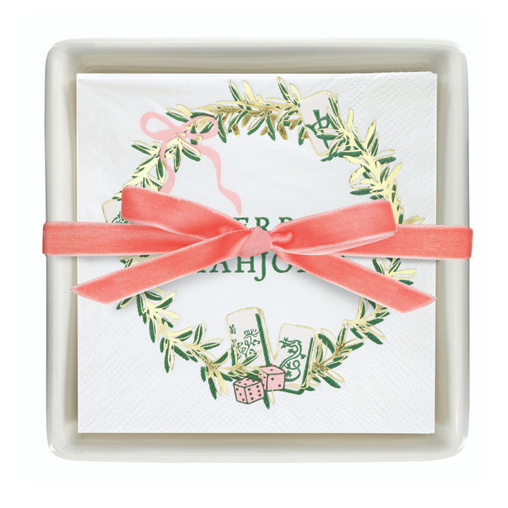 Merry Mahjong Napkin Tray, a white ceramic tray with holiday-themed napkins featuring a greenery wreath, mahjong tiles, and a pink velvet ribbon bow.