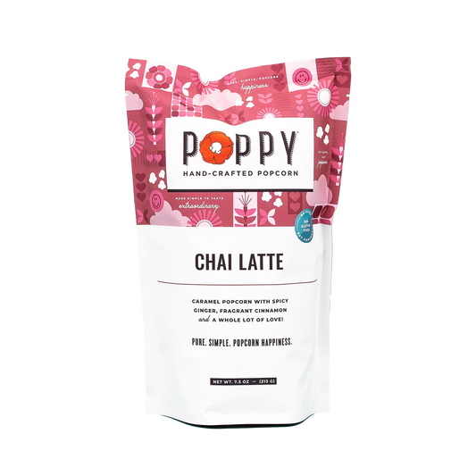 This is a packet of chai masala-flavored Poppy Popcorn. The packaging is colorful, dominated by pink and red floral designs. Flavor notes such as popcorn, ginger, cinnamon, and cardamom are prominently advertised on the label.