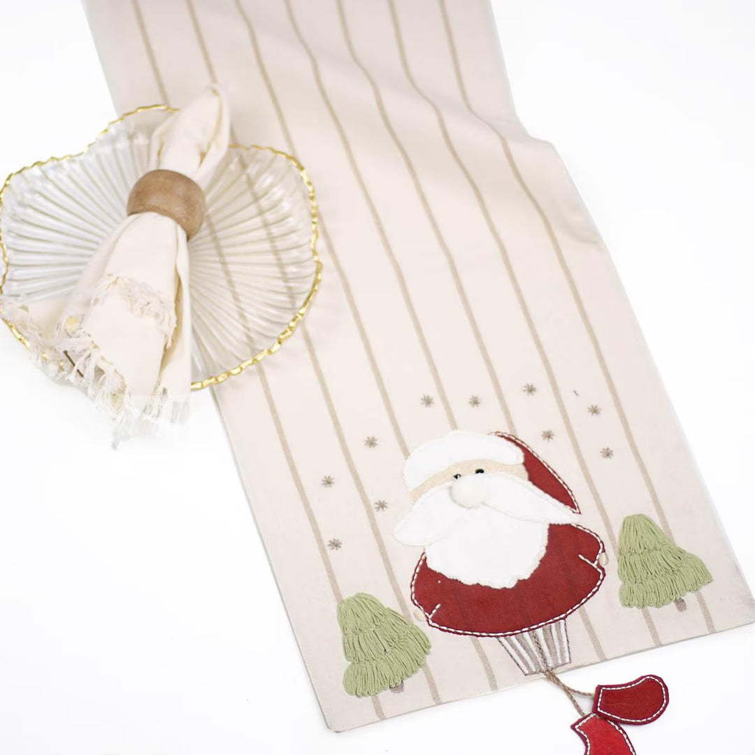 Old St. Nick Christmas Table Runner in cream with thin vertical stripes, featuring a Santa in a hot air balloon appliqué and two embroidered trees.
