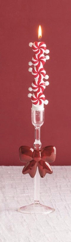 Christmas Mini Taper Candles featuring a lit taper stacked with red and white peppermint candy shapes in a clear glass holder with a red bow. Available in mini size.