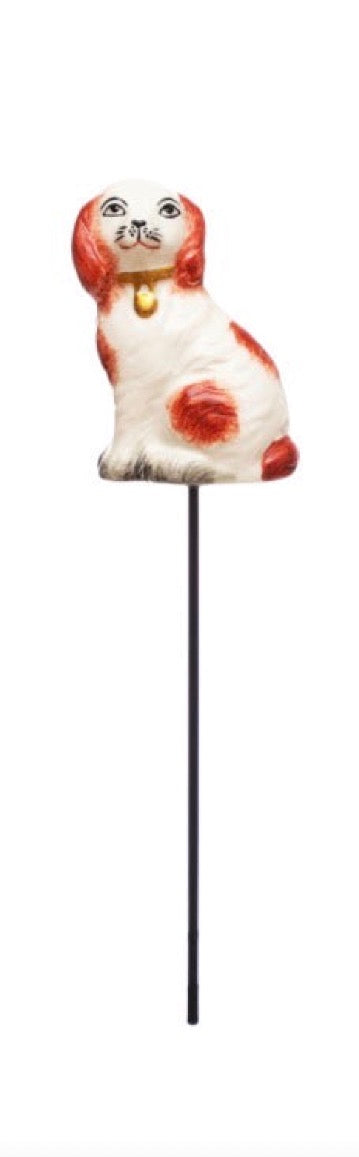 Stoneware plant stake shaped like a white dog with brown spots, sitting upright on a black stick. Available in small and large sizes.