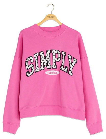 Pink cropped polka dot crew neck sweatshirt with “SIMPLY” in bold black and white varsity letters and “FOR GOOD” in small white text inside a pink oval; available in sizes S–XL.