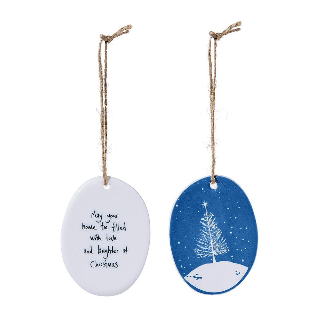 Two oval porcelain ornaments: one white with “May your home be filled with love and laughter at Christmas” text, and one blue with a snowy pine tree illustration.