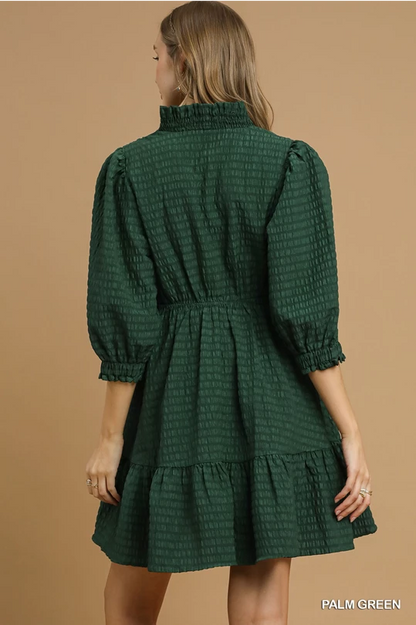 Palm Green Babydoll Dress with puffed 3/4 sleeves, ruffled high collar, and tiered skirt. Available in sizes XS-XL.