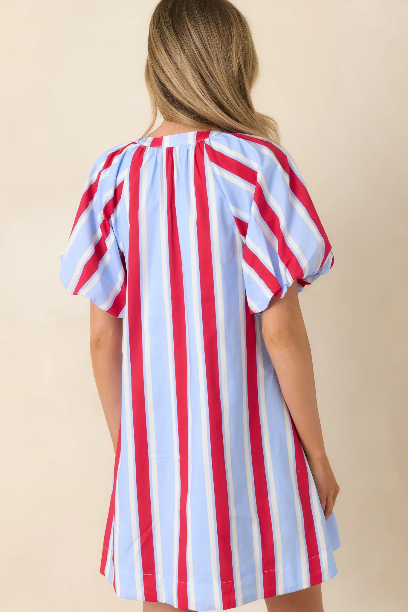American Darling Stripe Dress with puff sleeves, vertical red, blue, and white stripes on beige. Available in sizes XS-XL.