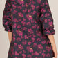 Floral Jacquard 3/4 Sleeve Dress featuring a bold floral pattern in shades of magenta and gold on a black background, with a high neckline and ruffled details. Ends above the knee. Available sizes: XS, S, M, L, XL.