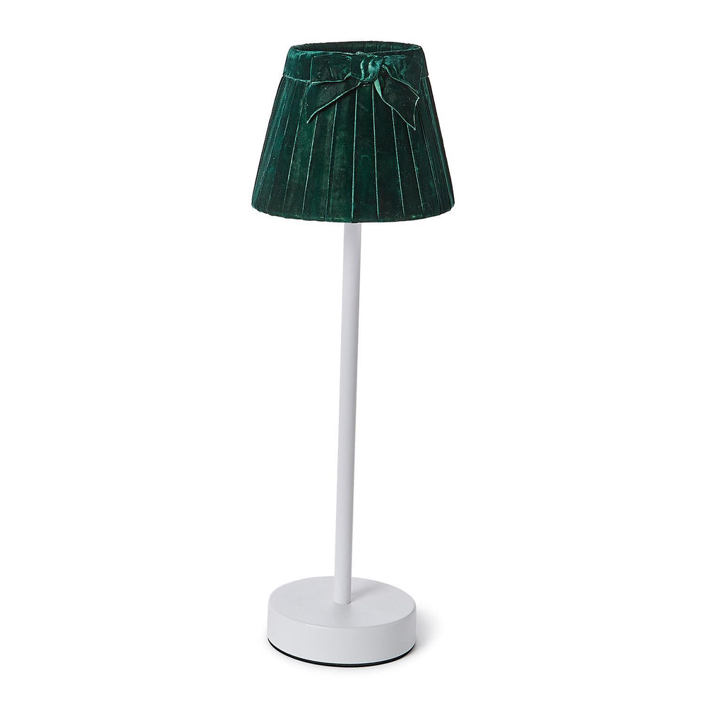 Tall white table lamp with a round base, topped with a dark green pleated velvet bow lampshade; available in small, medium, and large sizes.