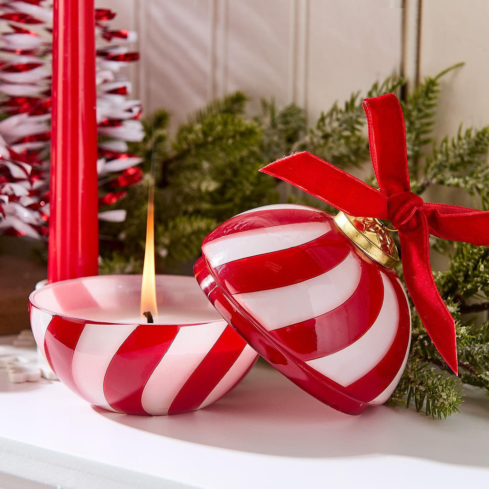 Red-and-white striped Sugar Cookie Ornament Candle with open lid and lit wax base.