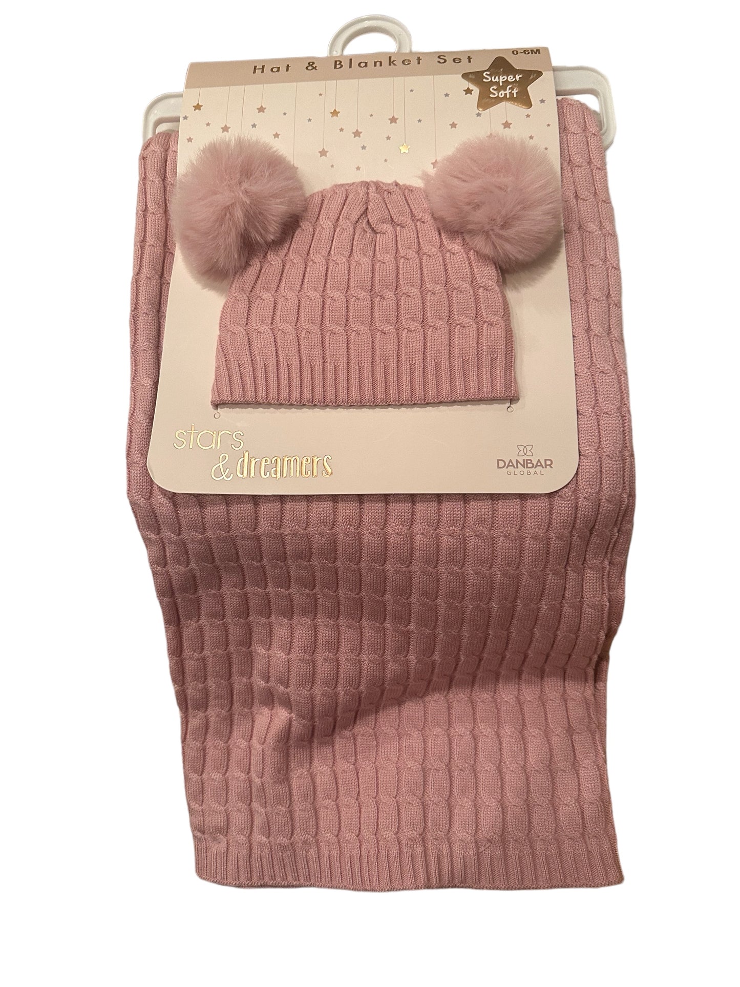 A pink baby Hat & Blanket Set with two pom-poms and a matching pink knitted blanket packaged together, labeled "stars & dreamers" on a display hanger.